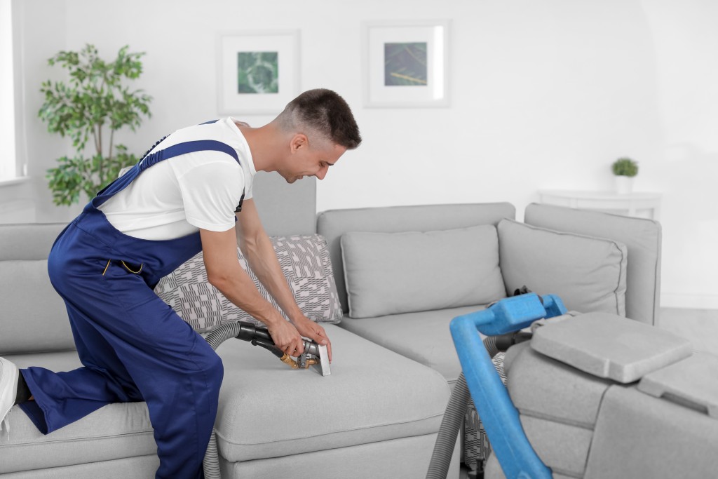 Man vacuuming the couch