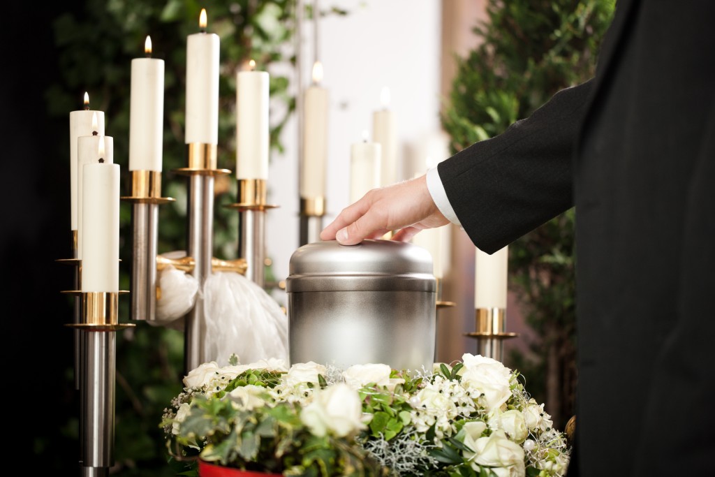 mortician carrying the urn to a bed of white roses