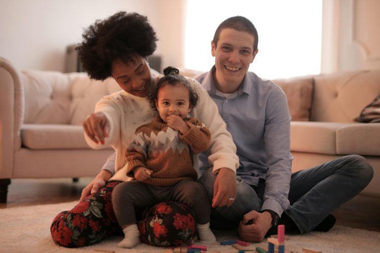 happy parents and toddler sitting on the living room floor